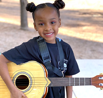 Girl smiling and holding a guitar