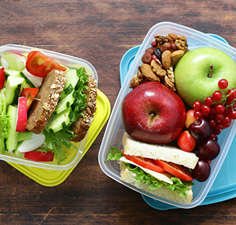 Apples, nuts, grapes, berries, and sandwiches in plastic containers